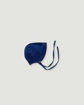 A navy blue corduroy bonnet with long ties, photographed flat on a light gray background.