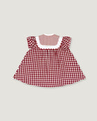 A small children's dress with a red and white gingham pattern, featuring a solid red and white striped yoke with a white scalloped collar, set against a solid light gray background.