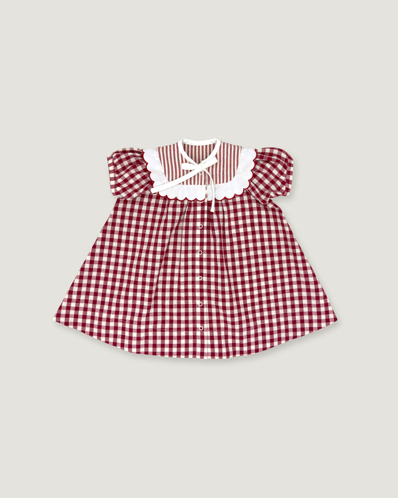 A toddler girl's dress featuring a red and white gingham pattern, a white ruffled collar with a striped inner lining, and puffed sleeves, shown flat on a light gray background.