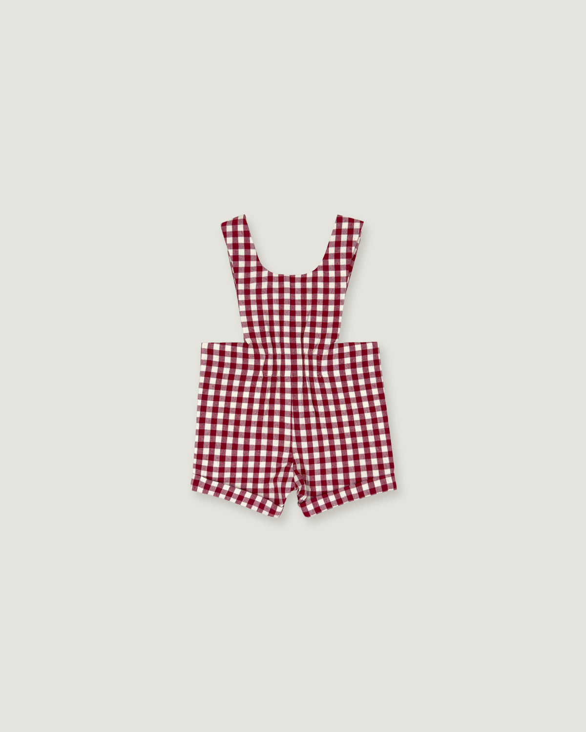 A red and white gingham check baby romper with shoulder straps, laid flat on a light gray background.