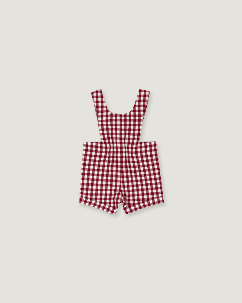 A red and white gingham check baby romper with shoulder straps, laid flat on a light gray background.
