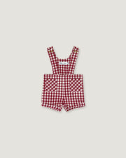 A baby romper in a red and white gingham check pattern, featuring adjustable shoulder straps and front patch pockets, displayed flat against a light gray background.