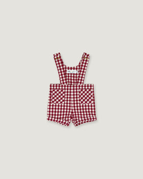 A baby romper in a red and white gingham check pattern, featuring adjustable shoulder straps and front patch pockets, displayed flat against a light gray background.