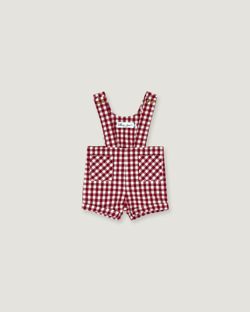 A baby romper in a red and white gingham check pattern, featuring adjustable shoulder straps and front patch pockets, displayed flat against a light gray background.