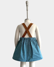
The Blue Jay pinafore displayed on a mannequin, highlighting the back view with an emphasis on the original brown leather-looking straps - This classic design, handmade from repurposed linen in our NYC studio, showcases the durability and visual appeal of the straps. The adjustable lengths ensure a perfect fit, while the generous pocket adds practicality, making this piece a stylish choice for summer wear.