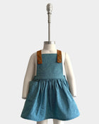 The Blue Jay pinafore displayed on a mannequin to showcase its perfect fit - Handmade from repurposed linen in our NYC studio, this classic design features durable leather-looking straps and adjustable lengths for an ideal silhouette. The generous pocket adds functionality while maintaining a stylish look, making it a versatile choice for summer wear.