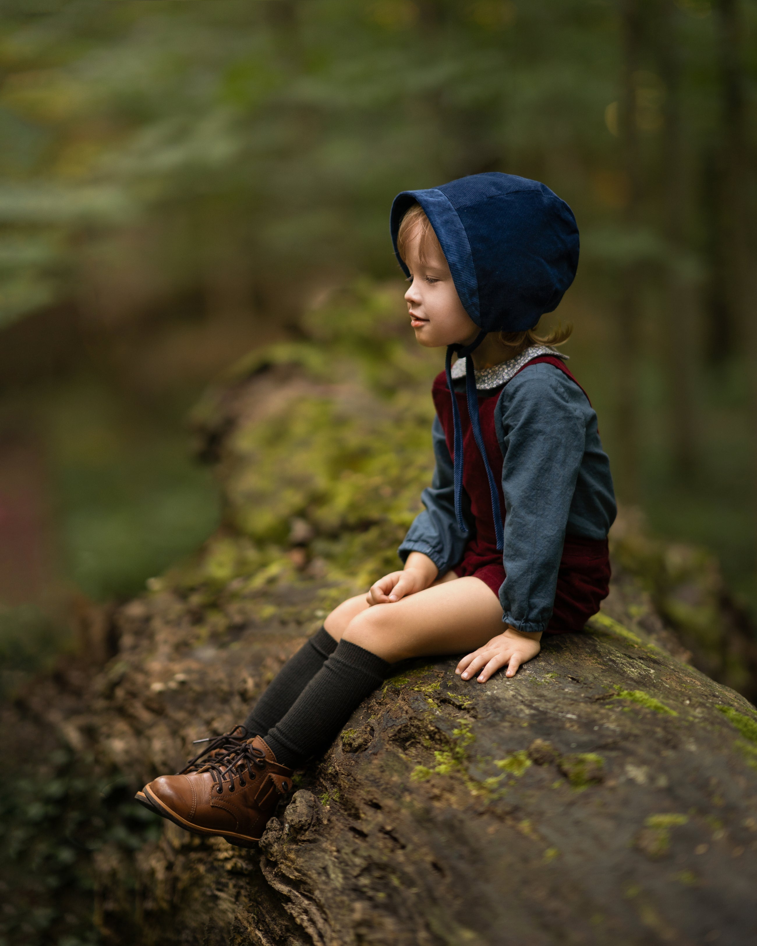 Boy in a blue bonnet sitting on a rock