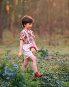 Child walking through a field of flowers holding a basket