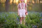 Child standing in a field of flowers holding a basket.