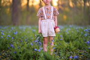 Child standing in a field of flowers holding a basket.