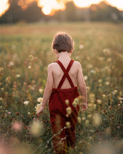 Child in red overalls standing in a field of wildflowers