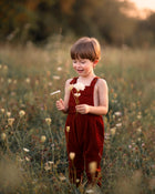 Child in a red dress holding flowers in a field