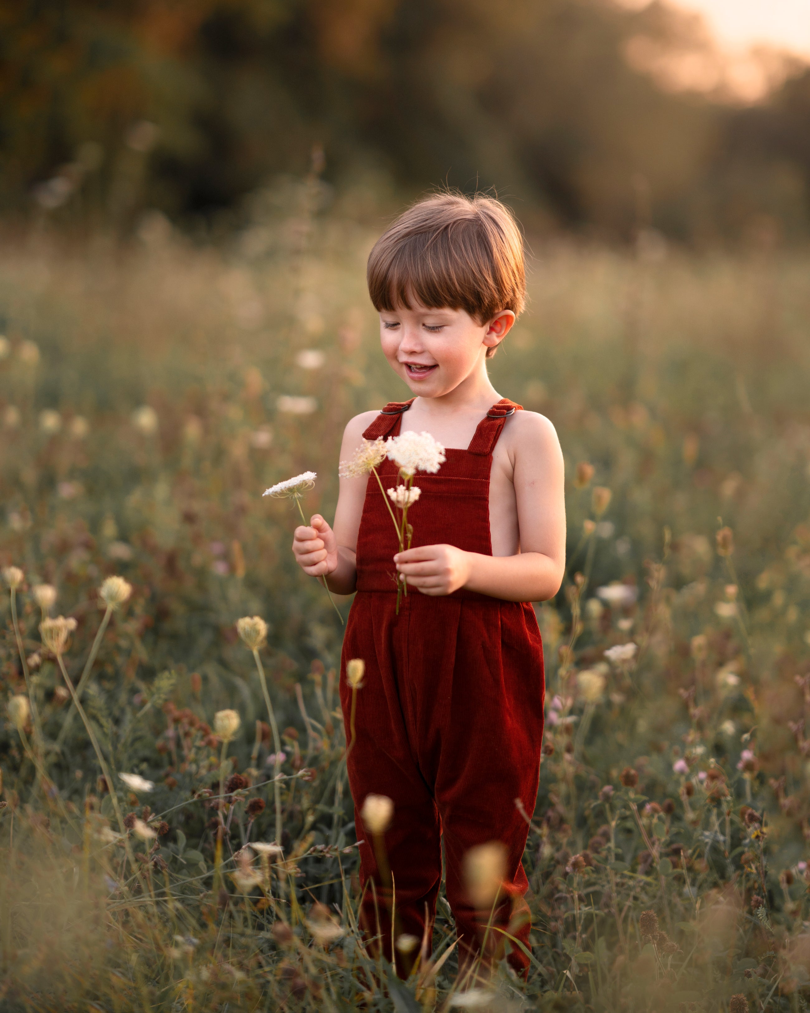 Child in a red dress holding flowers in a field
