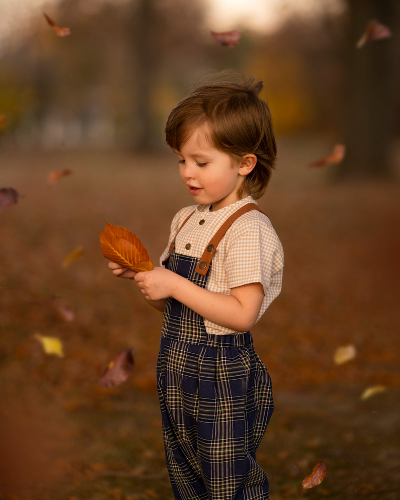 Child holding a leaf in an autumn setting with blurred background