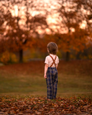 Child standing in a field with trees and sunset in the background