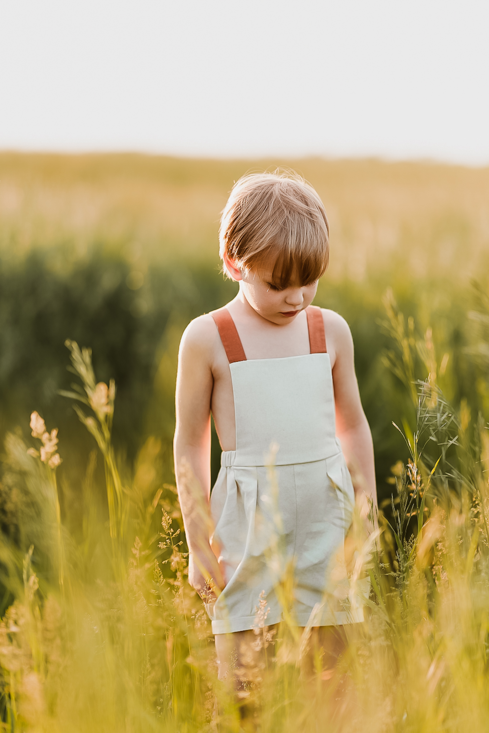 Boy in natural overalls in a yellow field