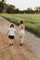 Boy and girl holding hands walking on a dirt road