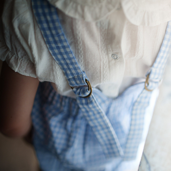 Close-up of a person wearing a white shirt with a blue checkered apron.