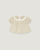 A baby girl's short-sleeve blouse in beige and white vertical stripes, featuring a white ruffled Peter Pan collar with a beige and white gingham pattern, set against a solid light gray background.