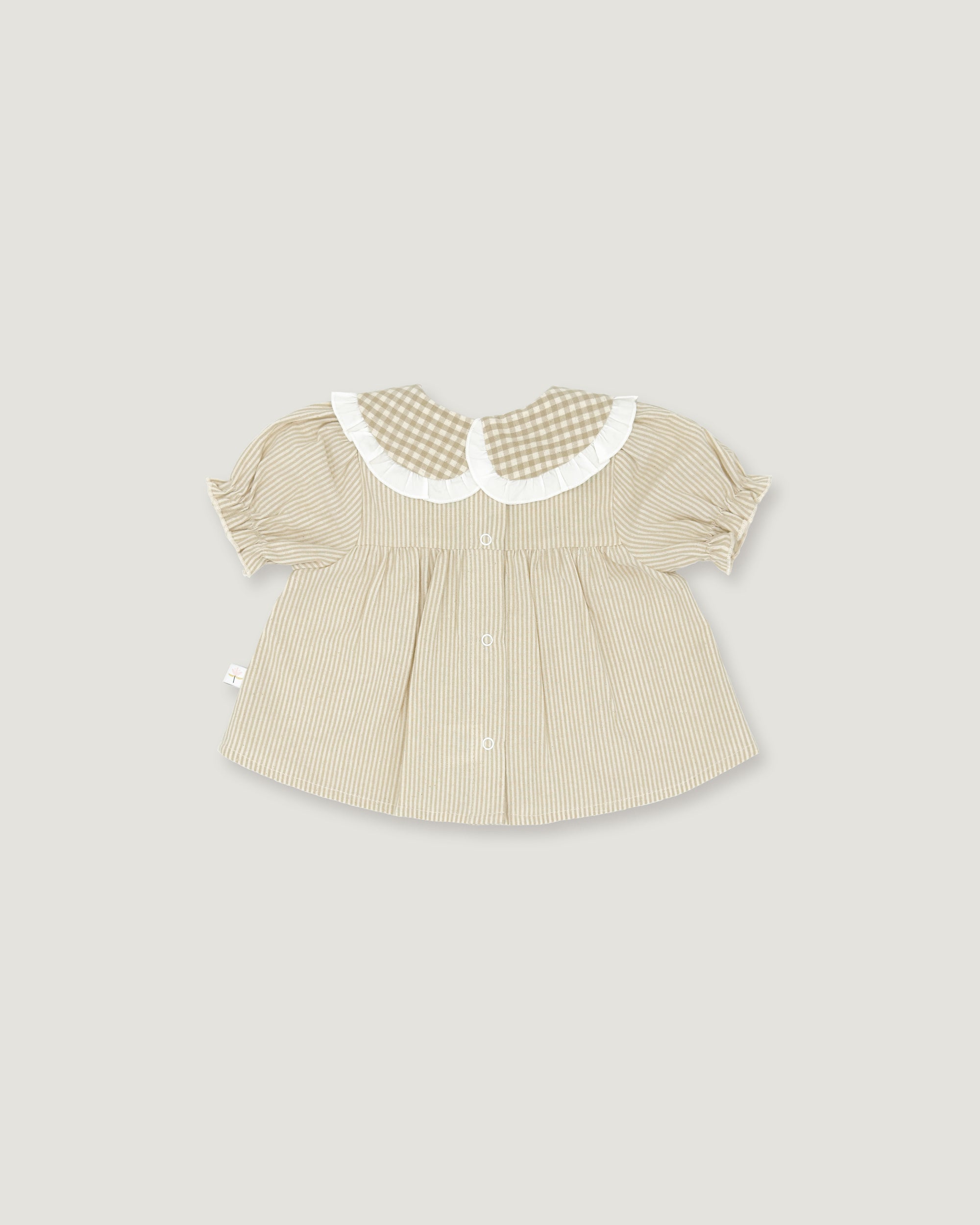 A baby girl's short-sleeve blouse in beige and white vertical stripes, featuring a white ruffled Peter Pan collar with a beige and white gingham pattern, set against a solid light gray background.
