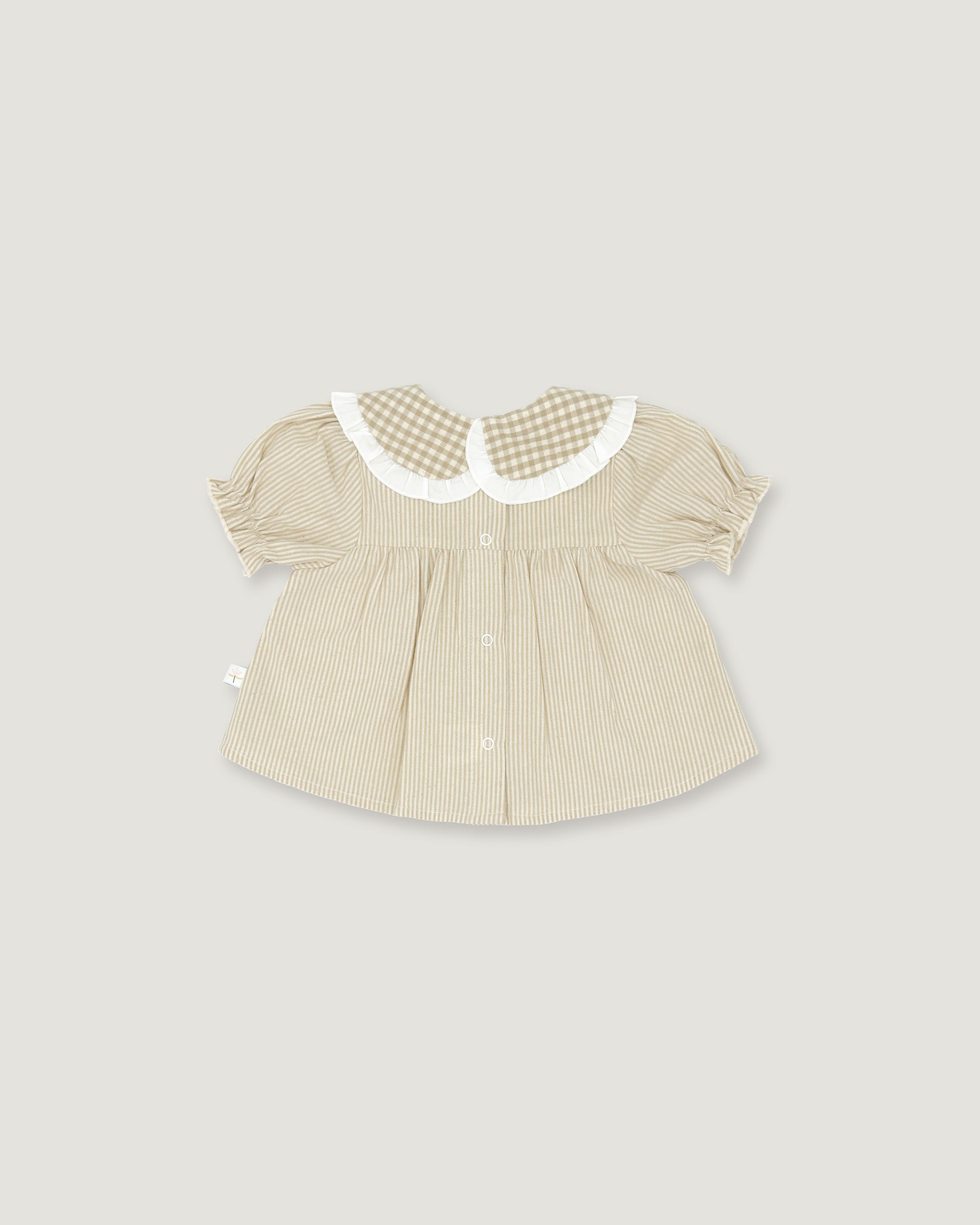 A baby girl's short-sleeve blouse in beige and white vertical stripes, featuring a white ruffled Peter Pan collar with a beige and white gingham pattern, set against a solid light gray background.