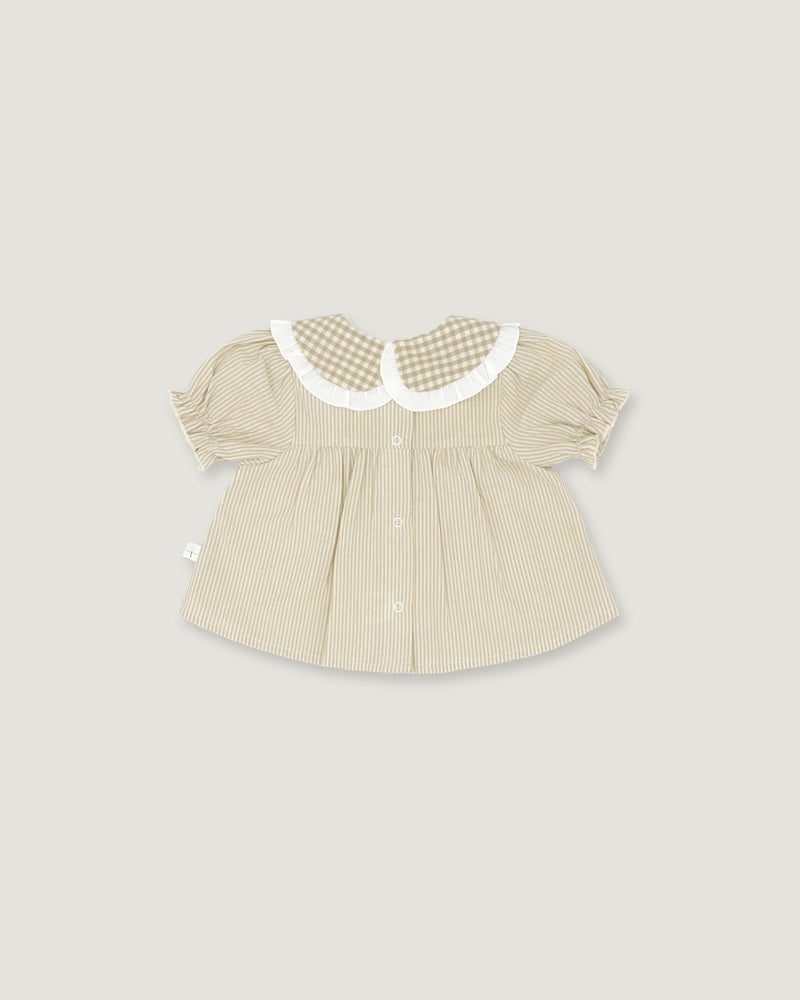 A baby girl's short-sleeve blouse in beige and white vertical stripes, featuring a white ruffled Peter Pan collar with a beige and white gingham pattern, set against a solid light gray background.