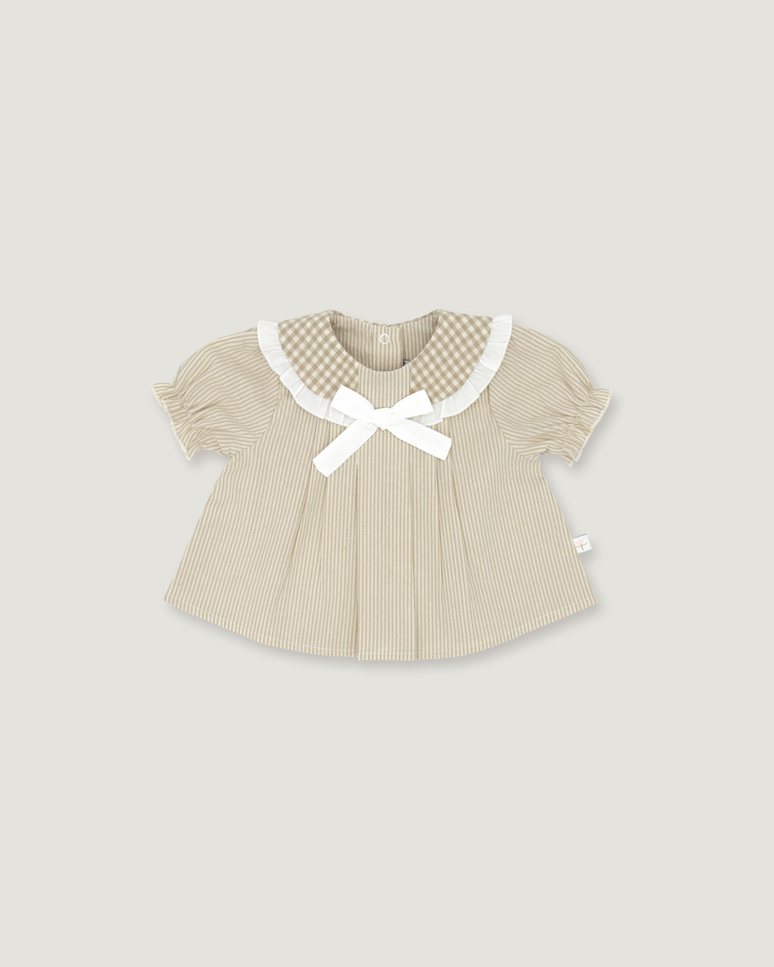 A baby girl's short-sleeve top in beige and white vertical stripes, featuring a white gingham Peter Pan collar, a white bow at the neckline, and a small white side tag, shown on a solid light gray background.