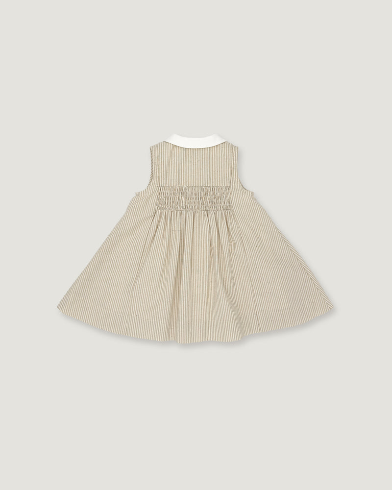 A sleeveless baby dress in beige and white vertical pinstripes, featuring a smocked bodice and a contrasting white collar, shown flat against a light gray background.