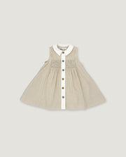 A sleeveless baby dress in beige and white vertical pinstripes, featuring a white Peter Pan collar, a smocked bodice, and a front button closure with gold-tone buttons, shown flat on a light gray background.