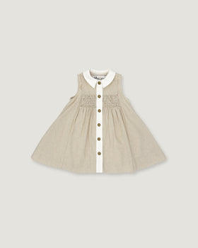 A sleeveless baby dress in beige and white vertical pinstripes, featuring a white Peter Pan collar, a smocked bodice, and a front button closure with gold-tone buttons, shown flat on a light gray background.