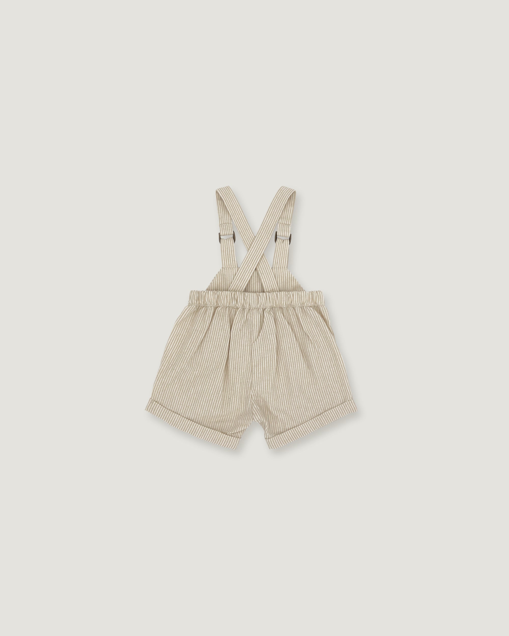 A pair of baby boy's cream-colored corduroy shorts with adjustable suspenders, laid flat against a light gray background.