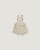 A pair of baby boy's beige corduroy suspenders shorts with adjustable shoulder straps and metal rings, shown flat on a light gray background.