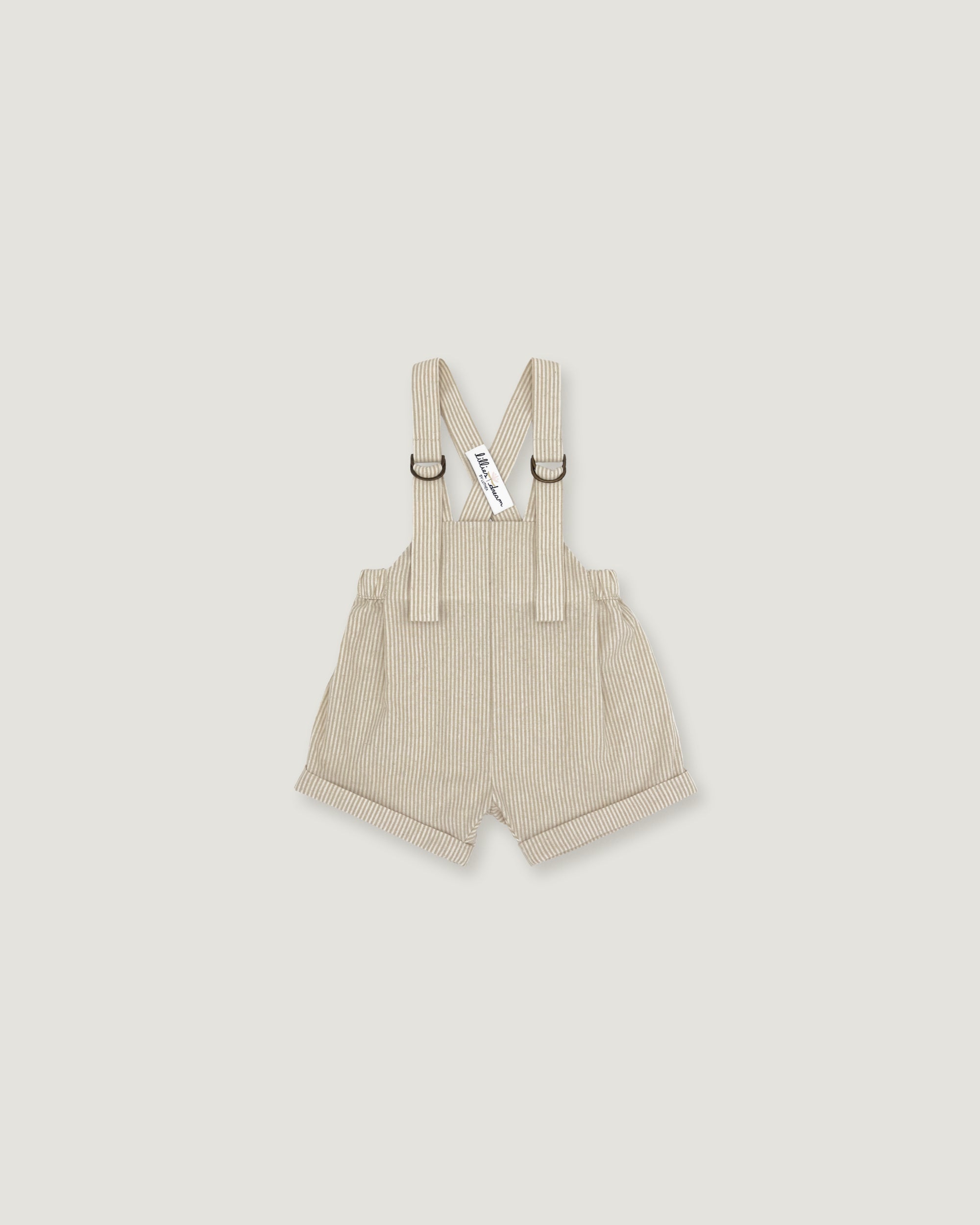 A pair of baby boy's beige corduroy suspenders shorts with adjustable shoulder straps and metal rings, shown flat on a light gray background.