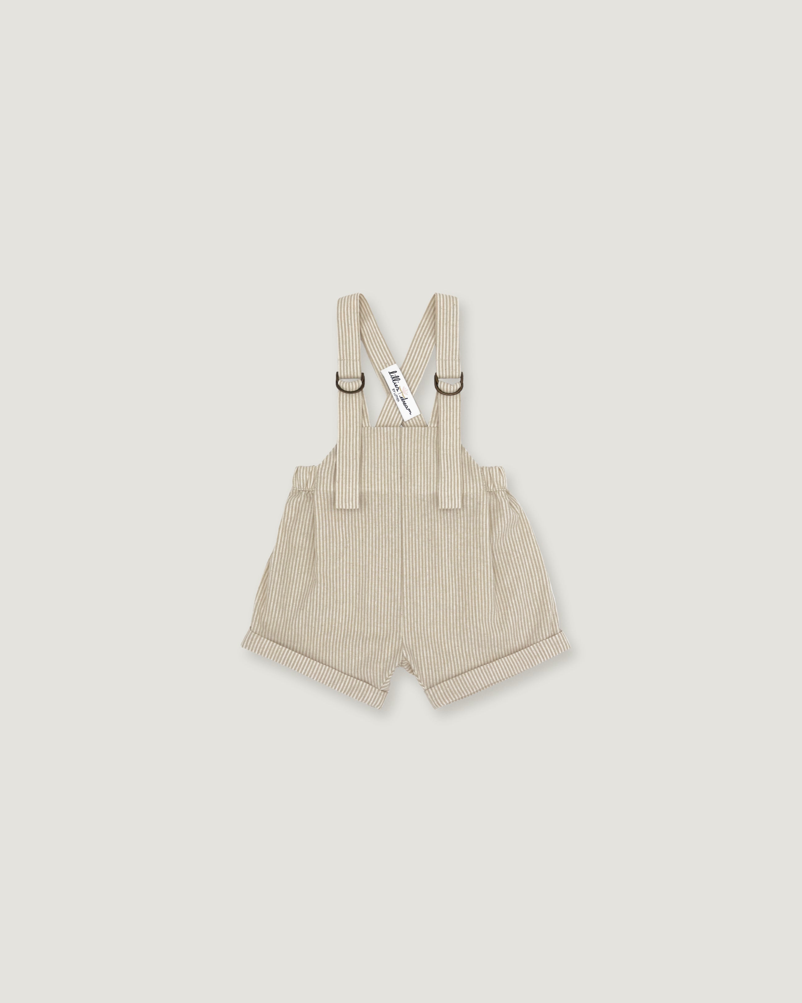 A pair of baby boy's beige corduroy suspenders shorts with adjustable shoulder straps and metal rings, shown flat on a light gray background.