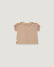 A light beige toddler girl's blouse with short ruffled sleeves and a ruffled collar, shown flat on a light gray background.
