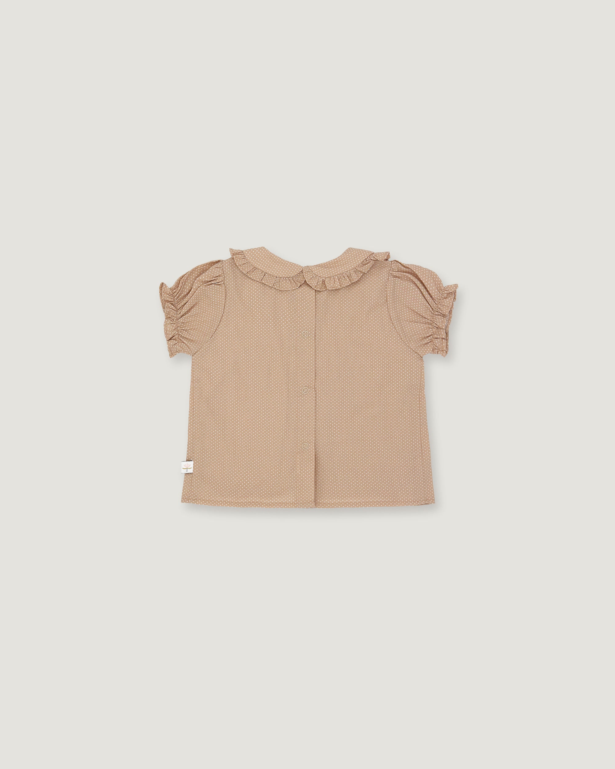 A light beige toddler girl's blouse with short ruffled sleeves and a ruffled collar, shown flat on a light gray background.