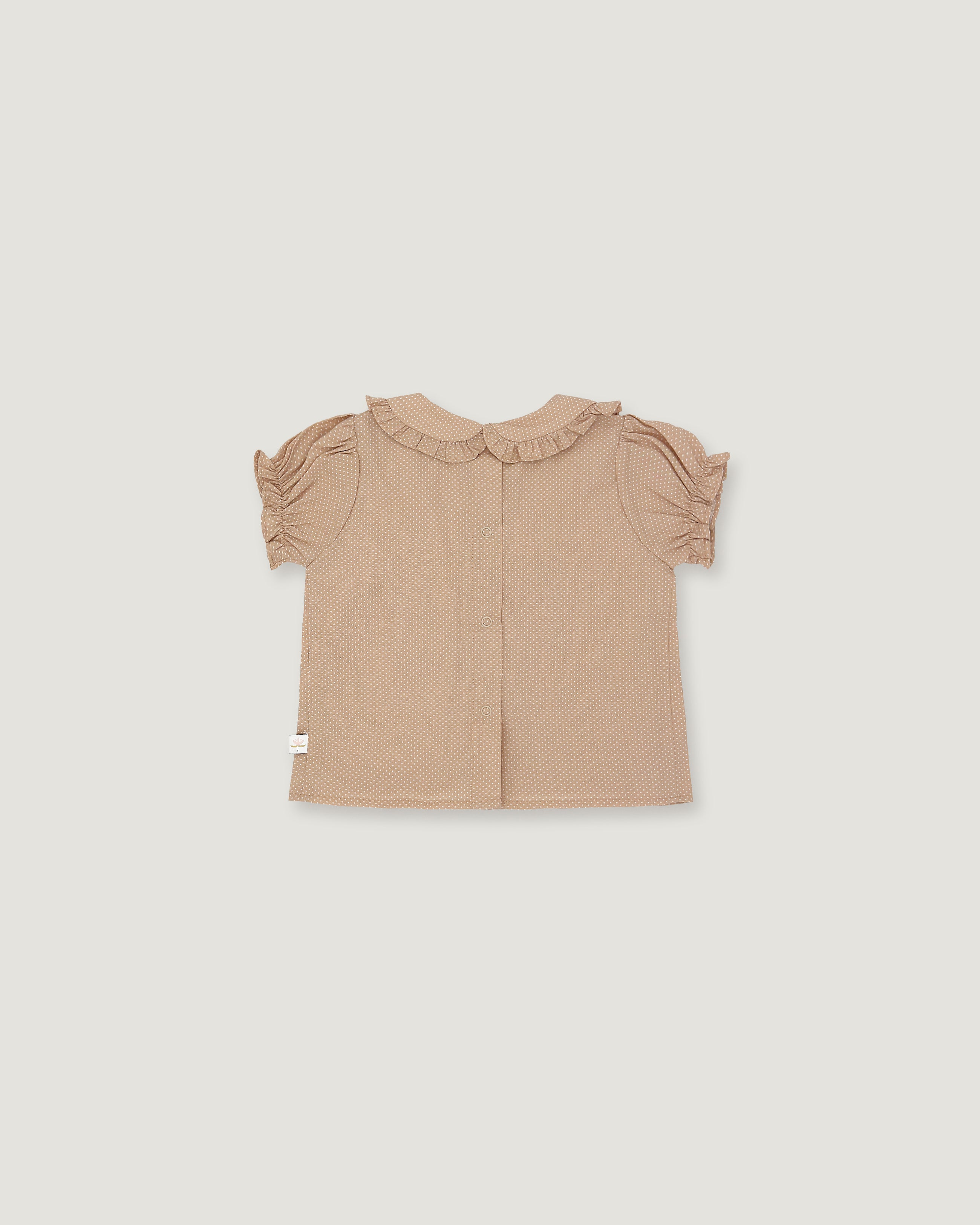 A light beige toddler girl's blouse with short ruffled sleeves and a ruffled collar, shown flat on a light gray background.