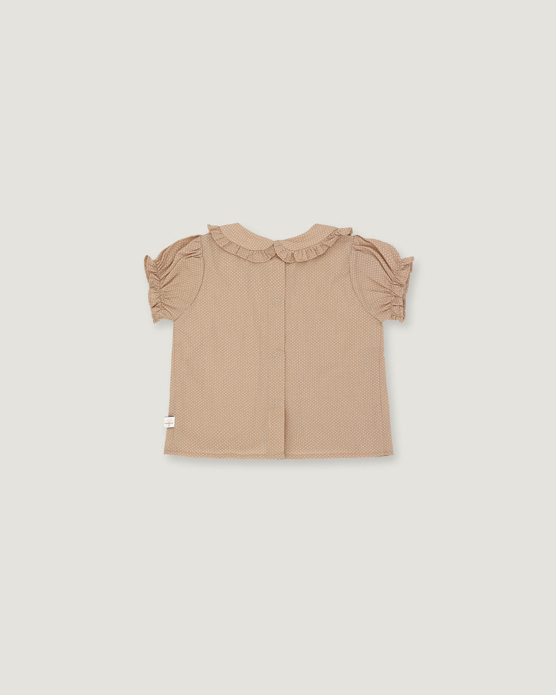 A light beige toddler girl's blouse with short ruffled sleeves and a ruffled collar, shown flat on a light gray background.