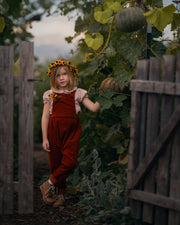 Child in a garden with pumpkins and a wooden fence