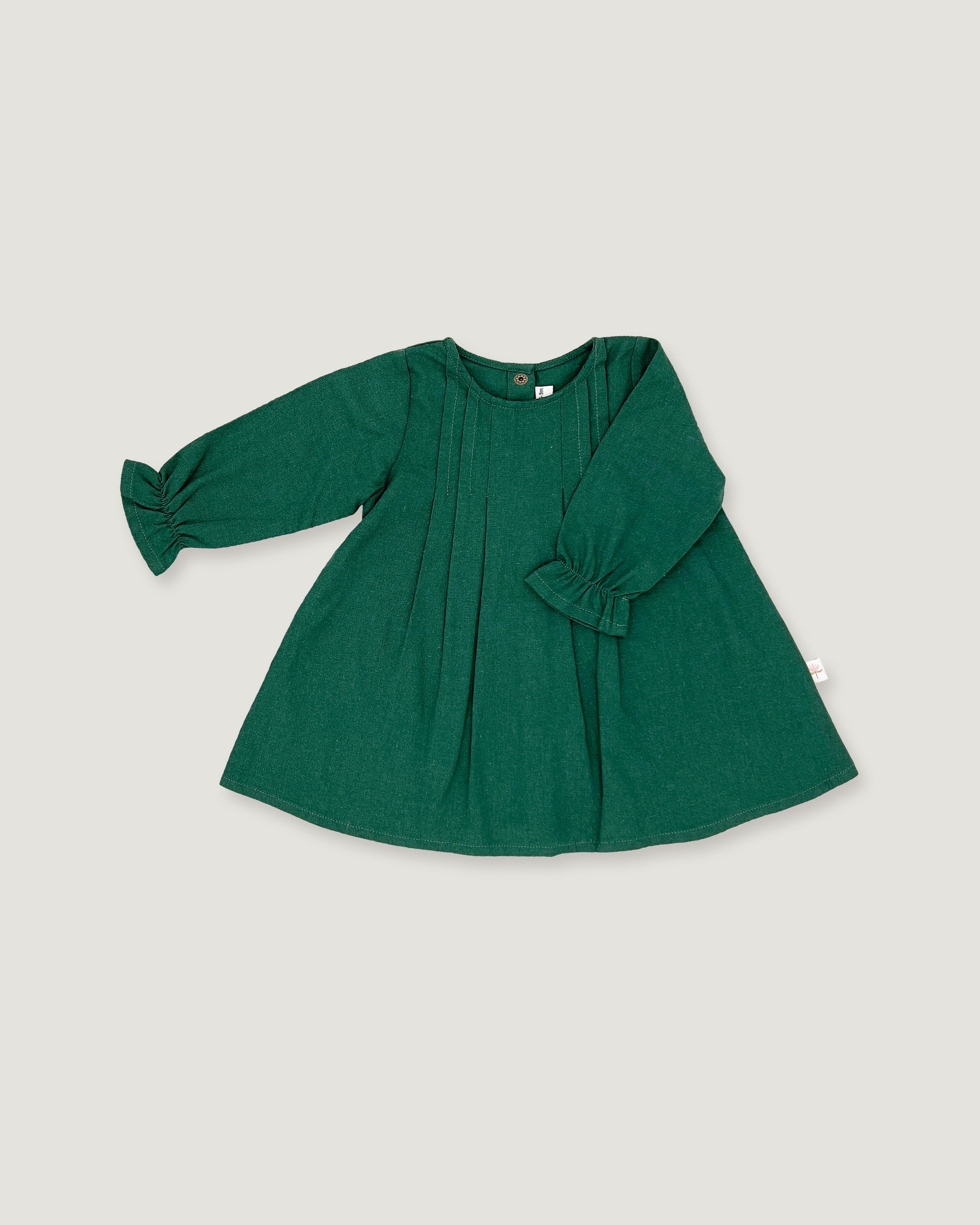 A dark green long-sleeve baby dress with pleated details and ruffled cuffs, laid flat on a light gray background.