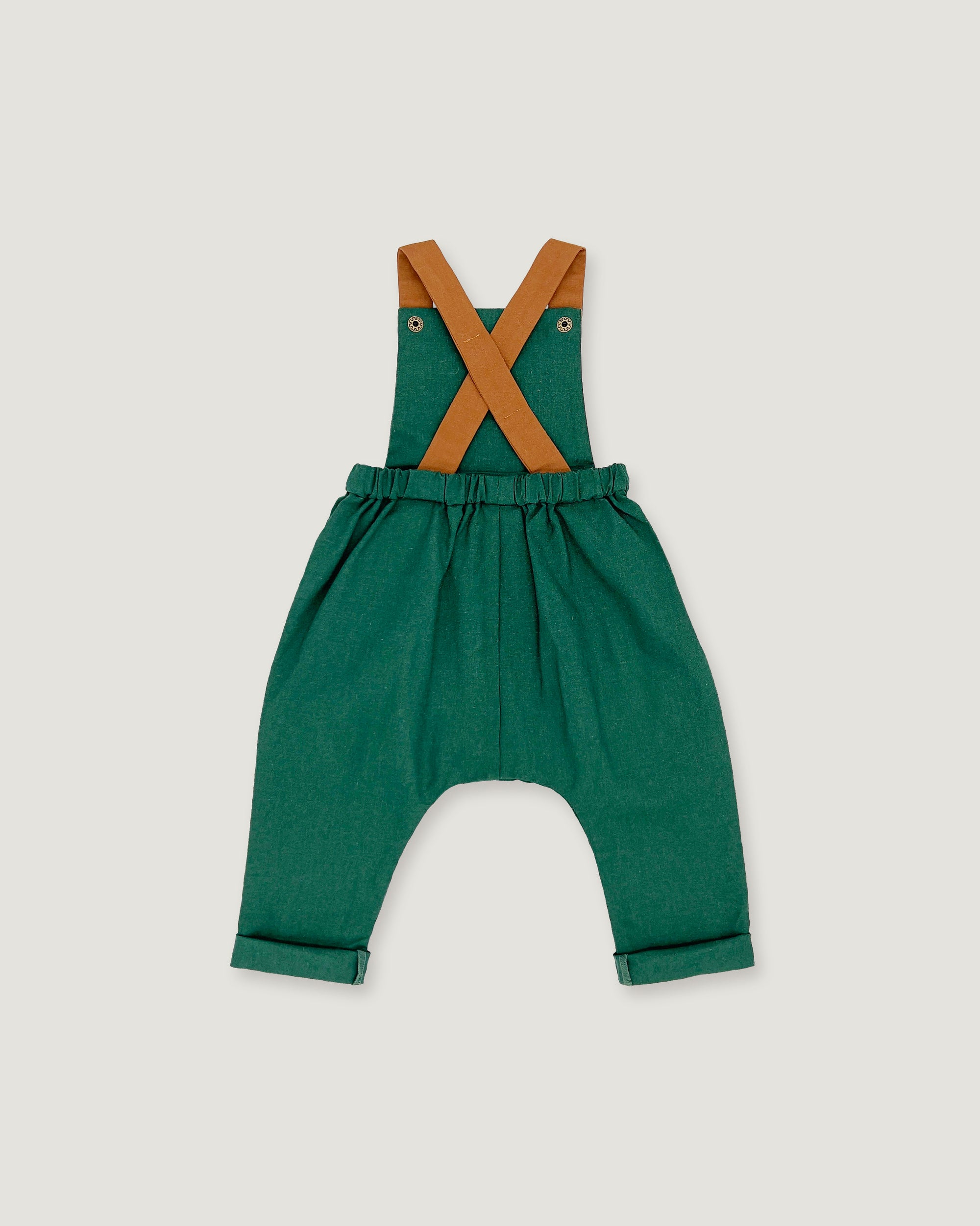A toddler's green harem-style romper with tan shoulder straps, shown flat on a light gray background.