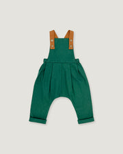A green baby romper with brown shoulder straps, photographed flat against a light gray background.
