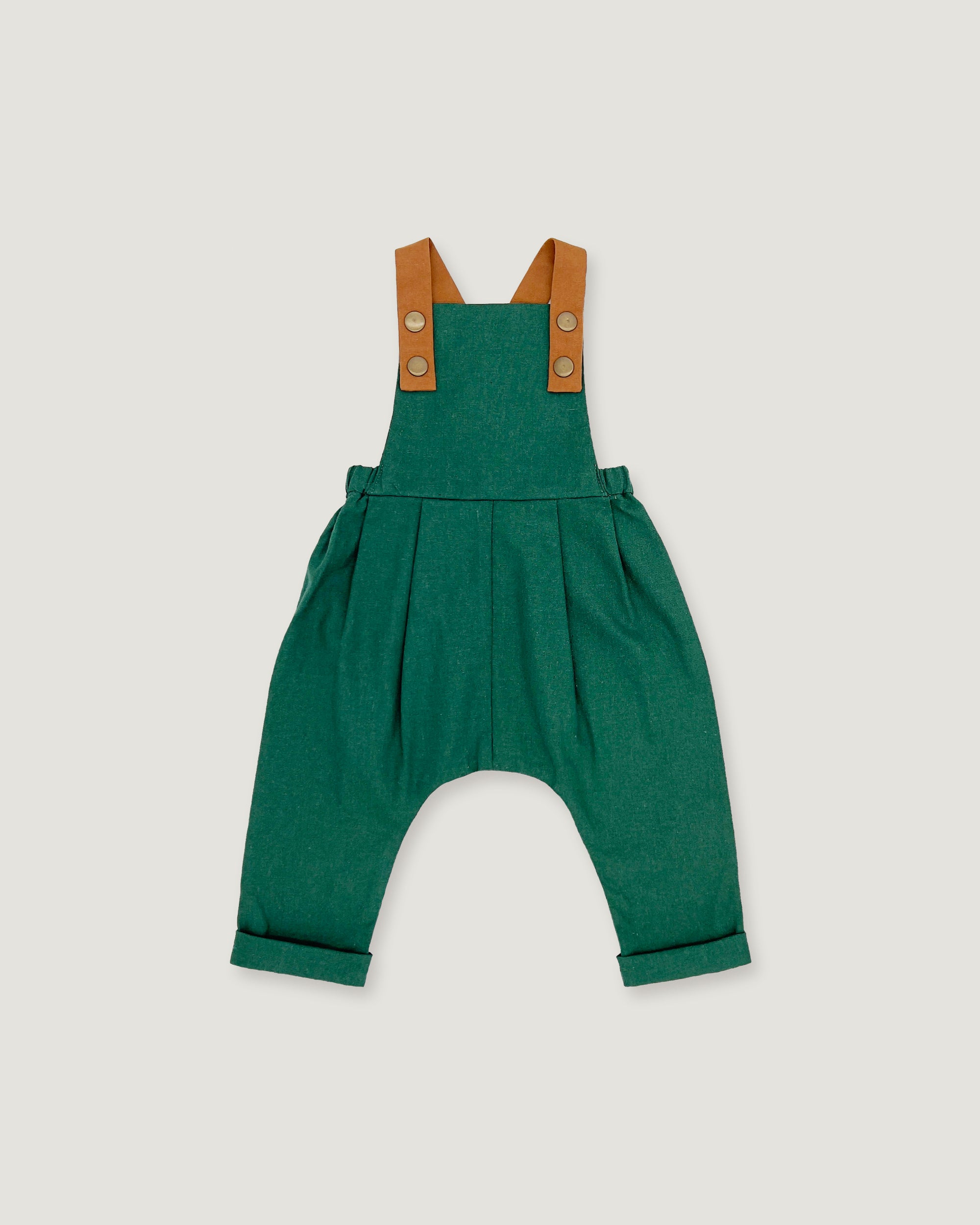 A green baby romper with brown shoulder straps, photographed flat against a light gray background.