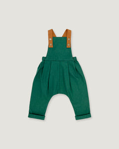 A green baby romper with brown shoulder straps, photographed flat against a light gray background.