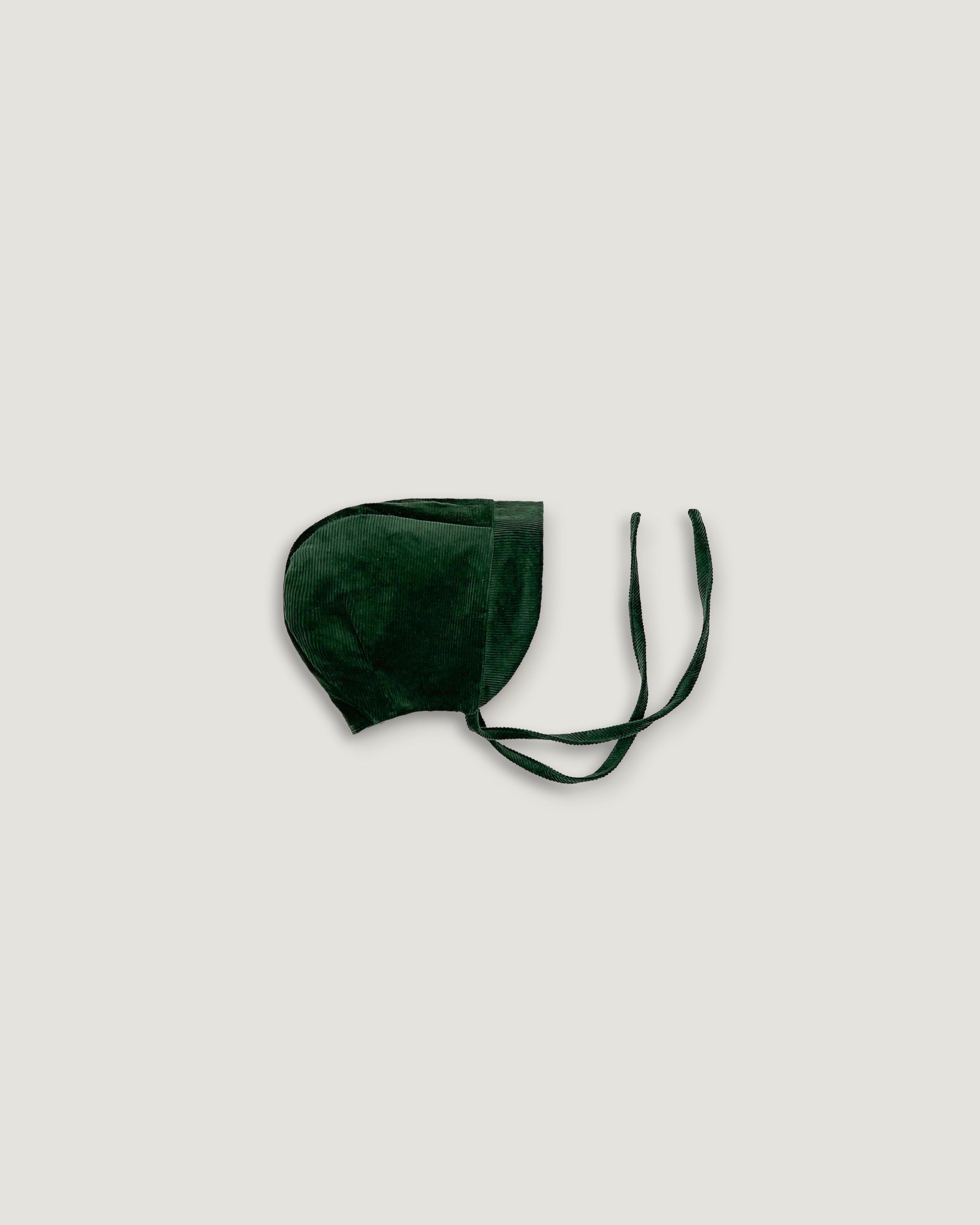 A dark forest green corduroy bonnet with adjustable ear loops, shown against a solid light gray background.