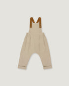 A pair of beige harem-style baby overalls with brown suspenders, shown flat against a light gray background.