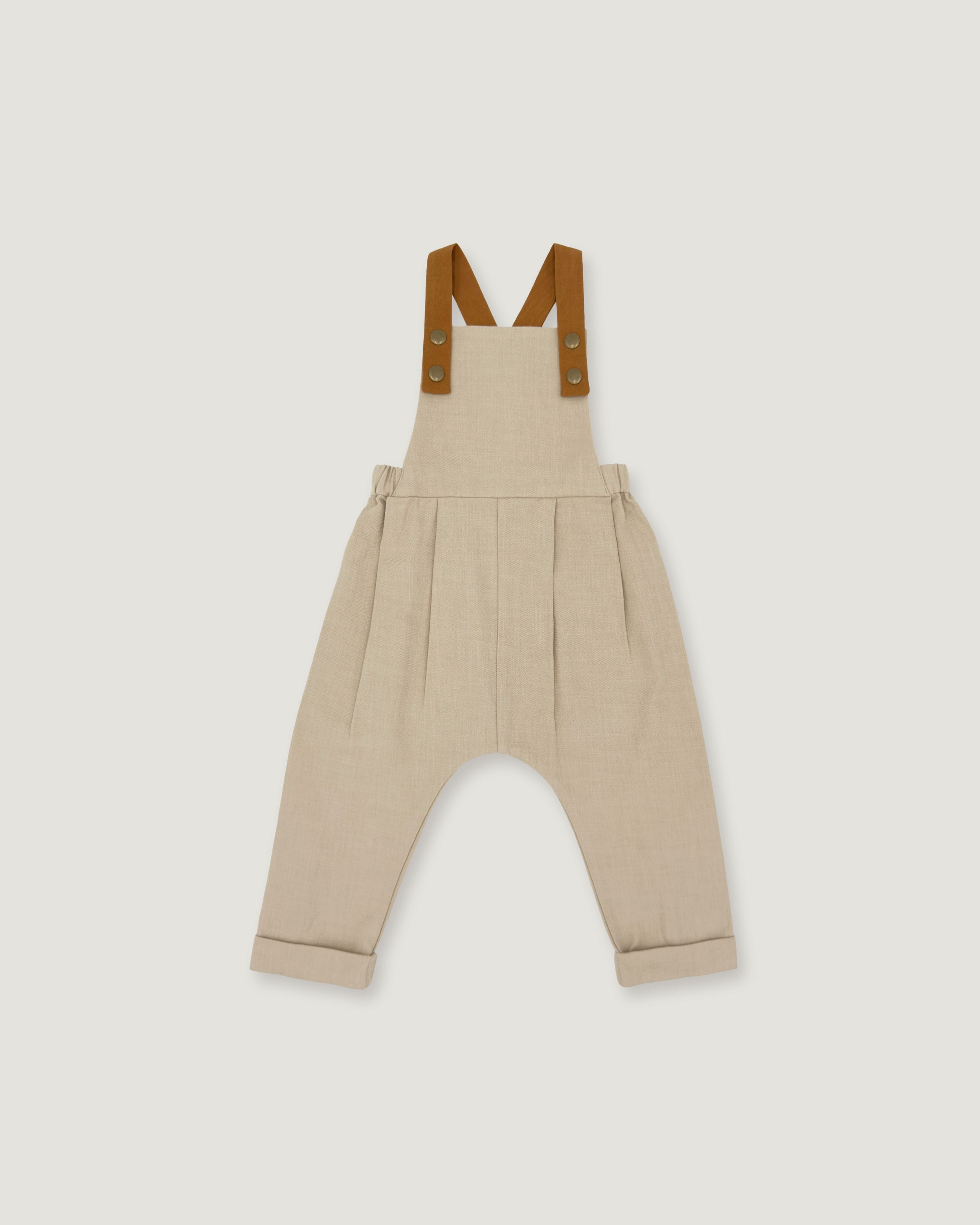 A pair of beige harem-style baby overalls with brown suspenders, shown flat against a light gray background.