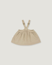 A light beige baby dress with adjustable shoulder straps and a gathered skirt, shown flat on a light gray background.