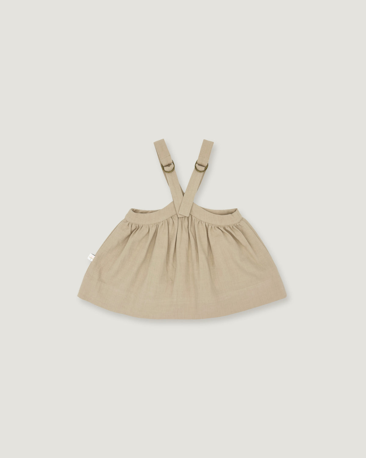 A light beige baby dress with adjustable shoulder straps and a gathered skirt, shown flat on a light gray background.