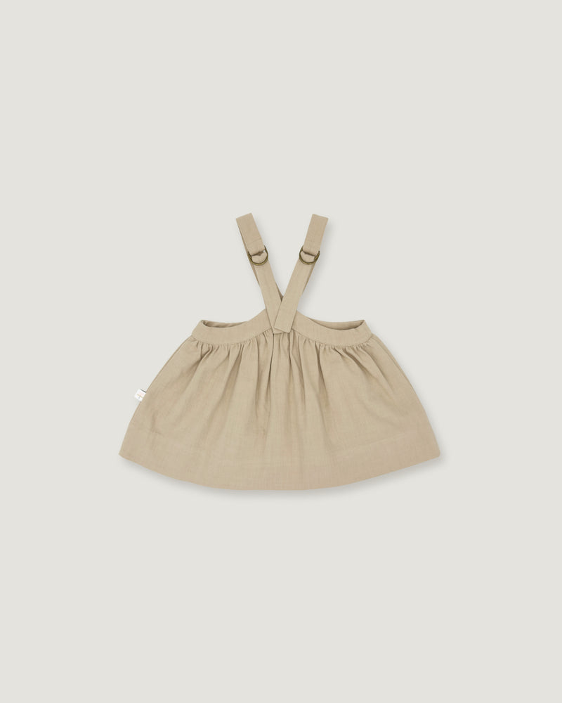 A light beige baby dress with adjustable shoulder straps and a gathered skirt, shown flat on a light gray background.